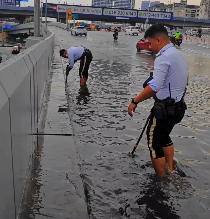 M'sian traffic police officers go beyond their duty by clearing clogged drains while barefoot