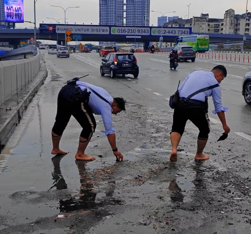 M'sian traffic police officers go beyond their duty by clearing clogged drains while barefoot