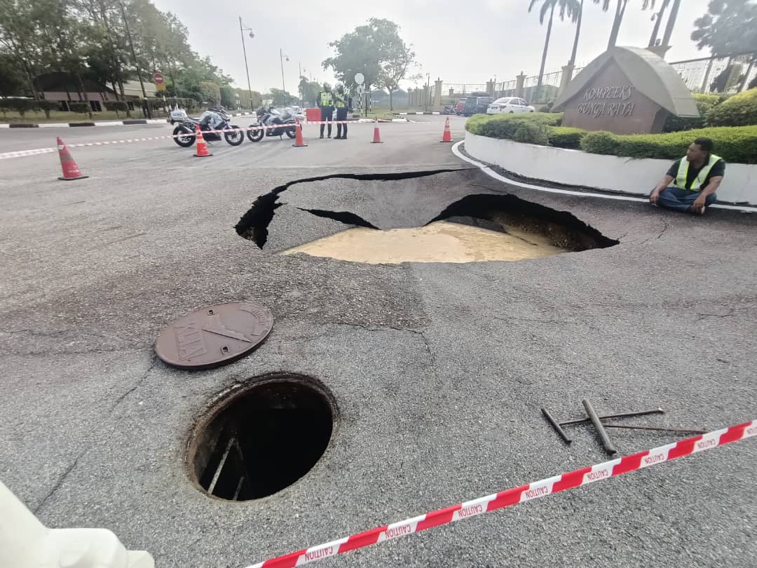 Jkr officer inspecting sinkhole at klia's bunga raya complex