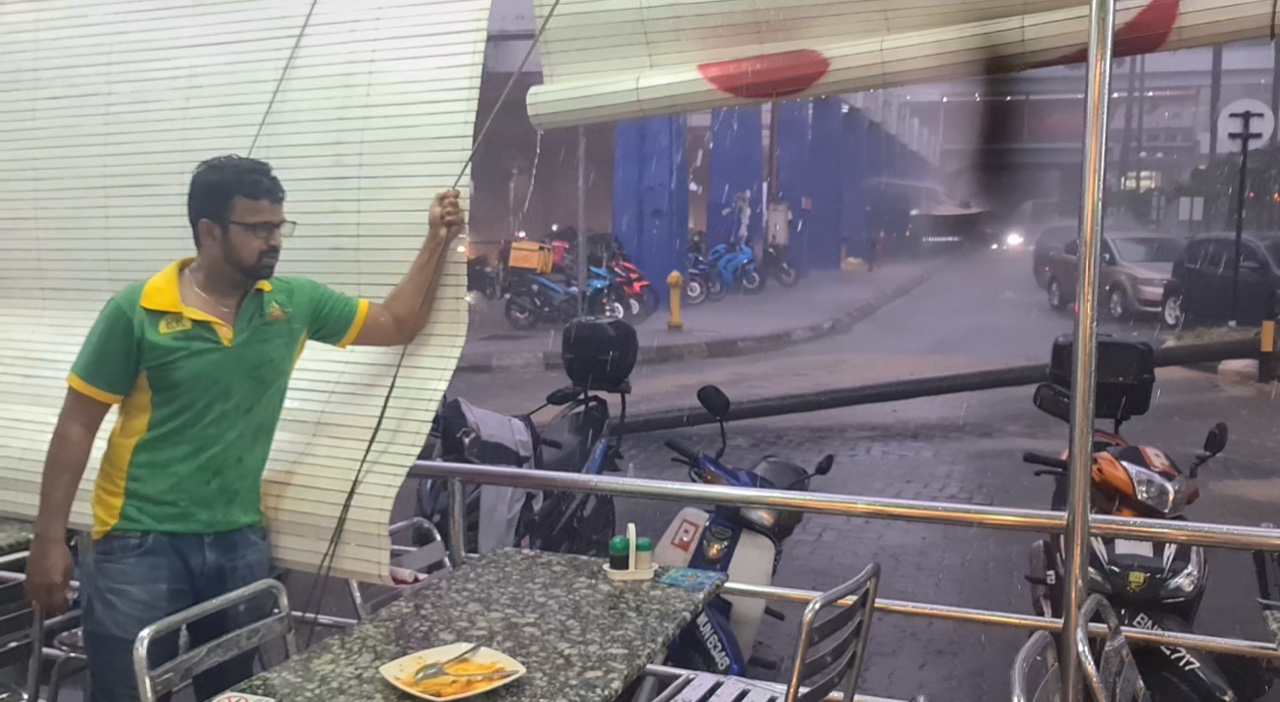 Nasi kandar worker holding the curtain to make sure the rain doesnt affect the customers