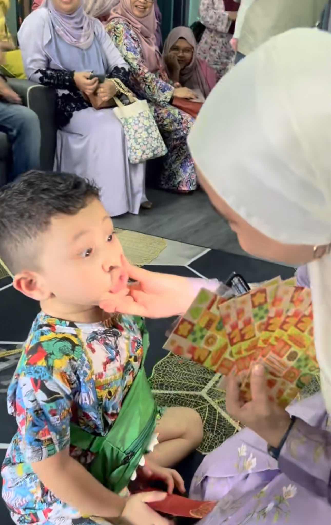 Boy shows his teeth before claiming his duit raya packet