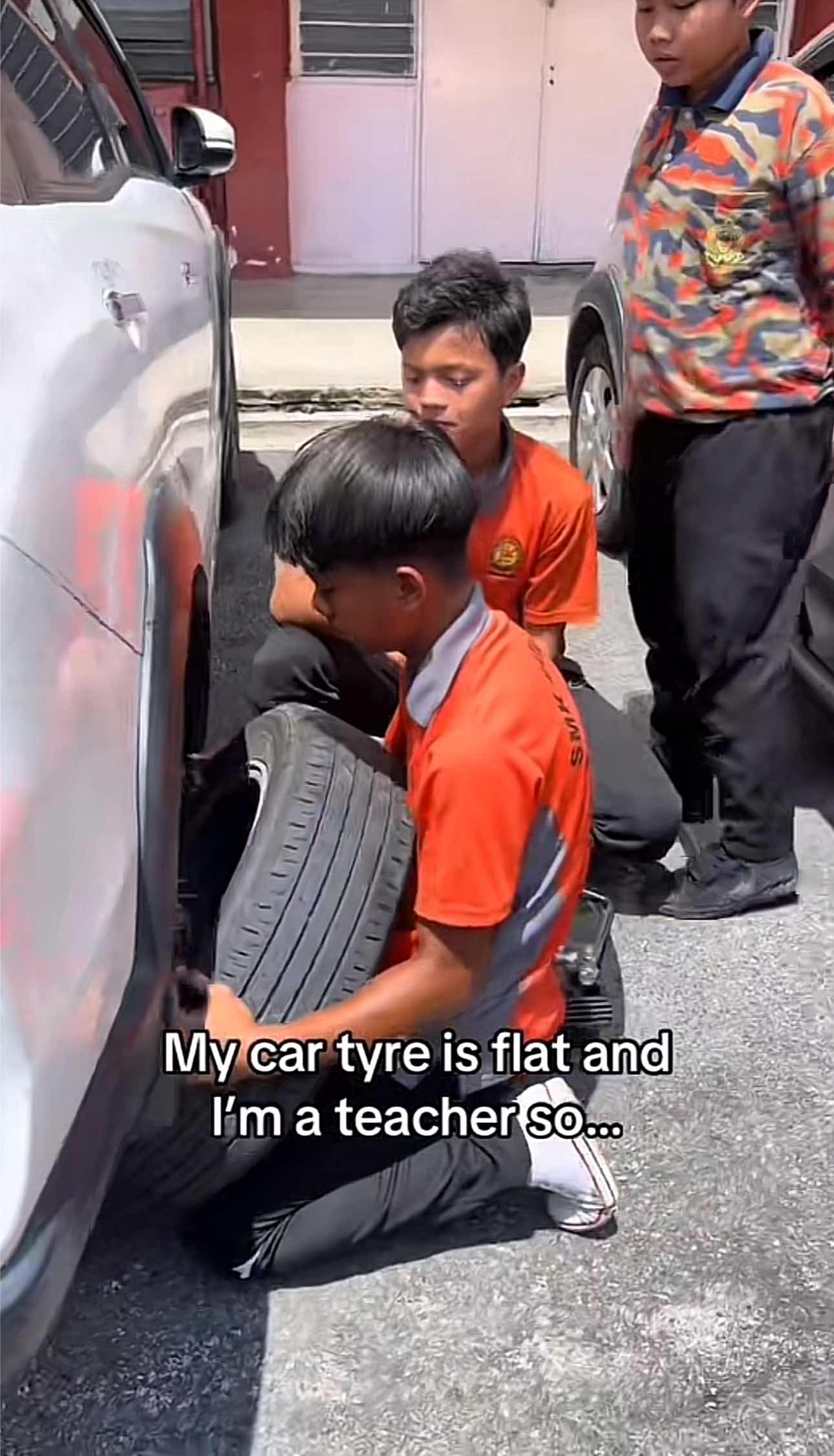 Students helping teacher to  fix the tyre