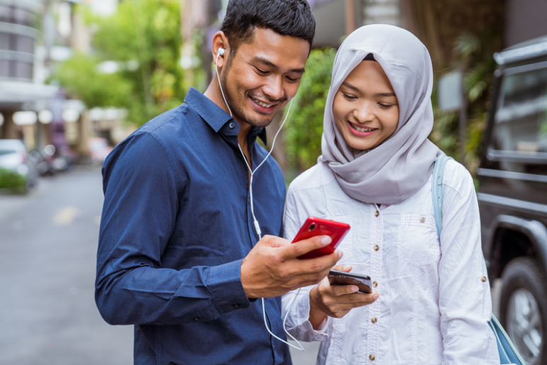 Malay man and woman using their handphone