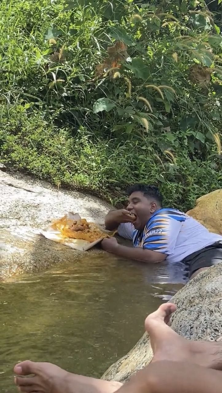 M'sian man takes a mouthful of nasi campur while floating inside river
