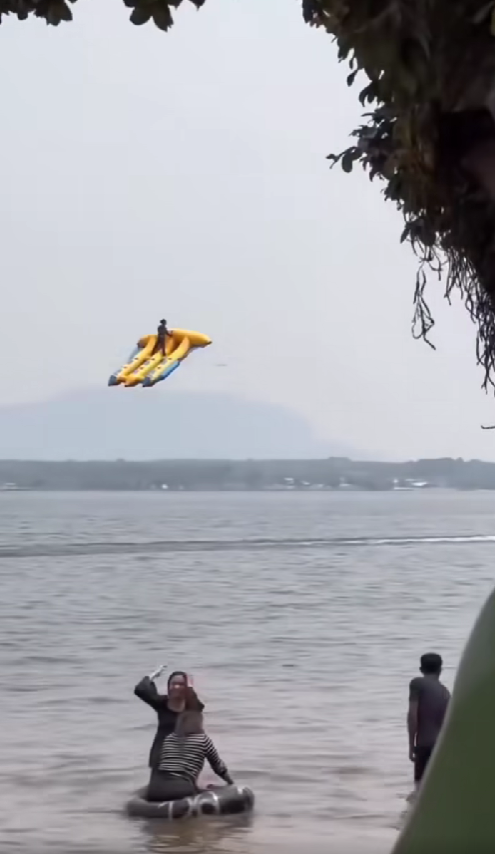 Man flying on top of triple inflatable banana boat
