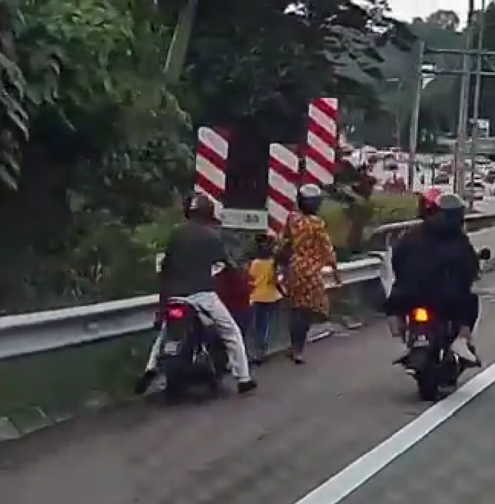 Man psuhing his motorbike on a highway while his wife and kid walking infront
