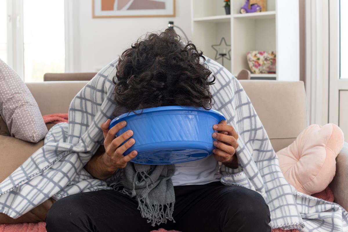 Man vomiting into a bucket