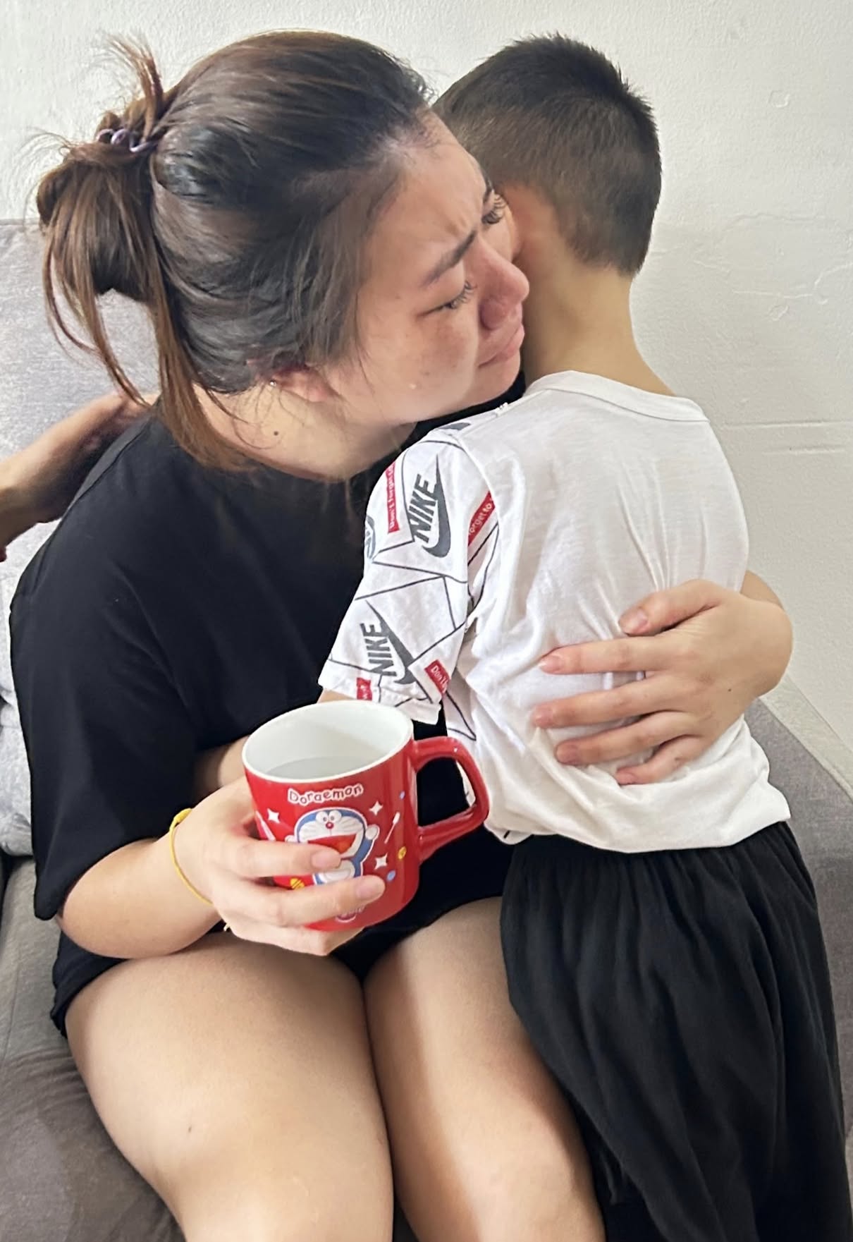 mom is crying while hugging her son