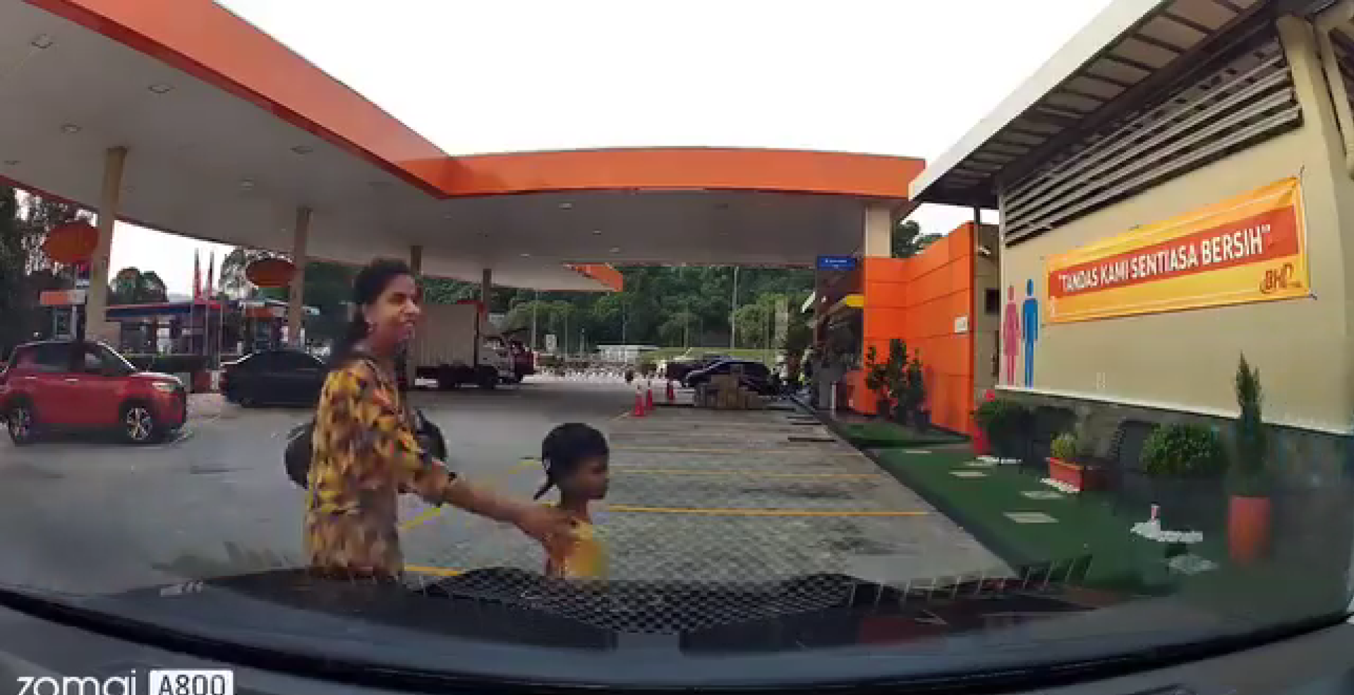 Mother and son walking in front of a car