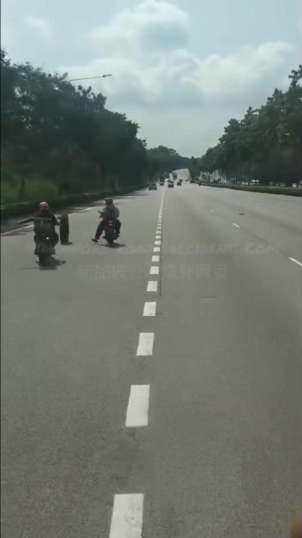 Motorcyclists guide car tyre away from highway