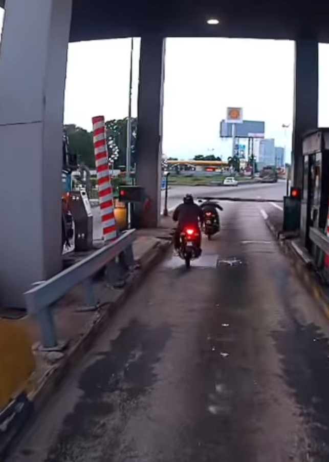 Motorcylist passing through car toll booth (1)