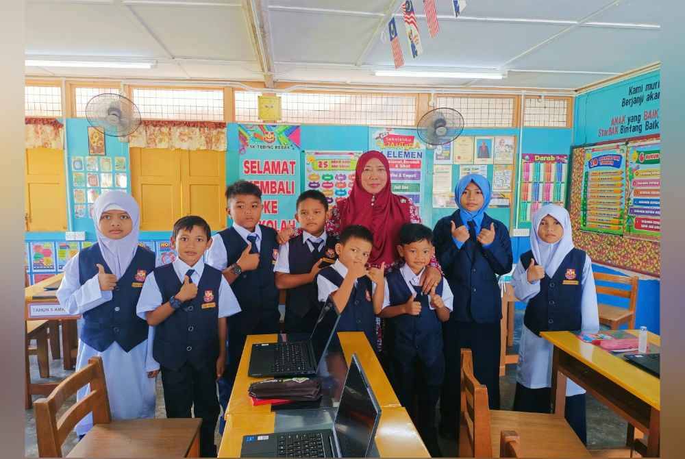Msian headmaster standing along woth the eight students in her school at a classrooom
