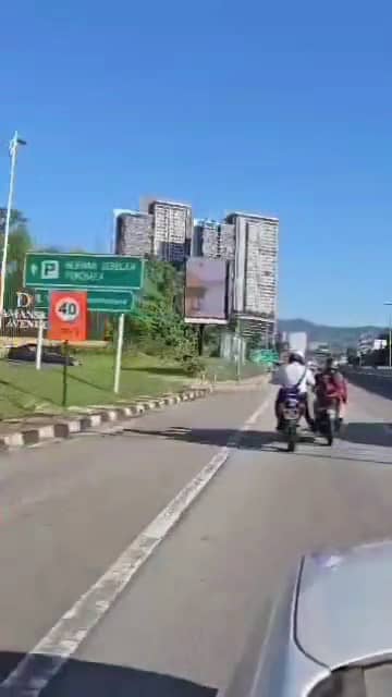 Msian police officer pushing a public's motor on a highway