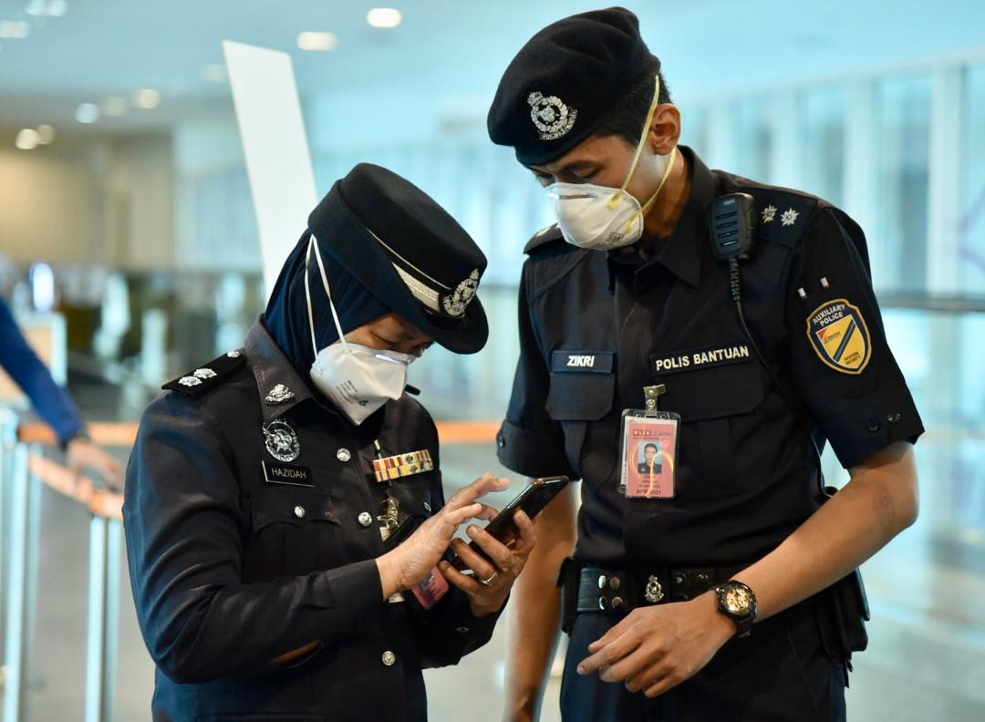 M'sian police officers checking a handphone