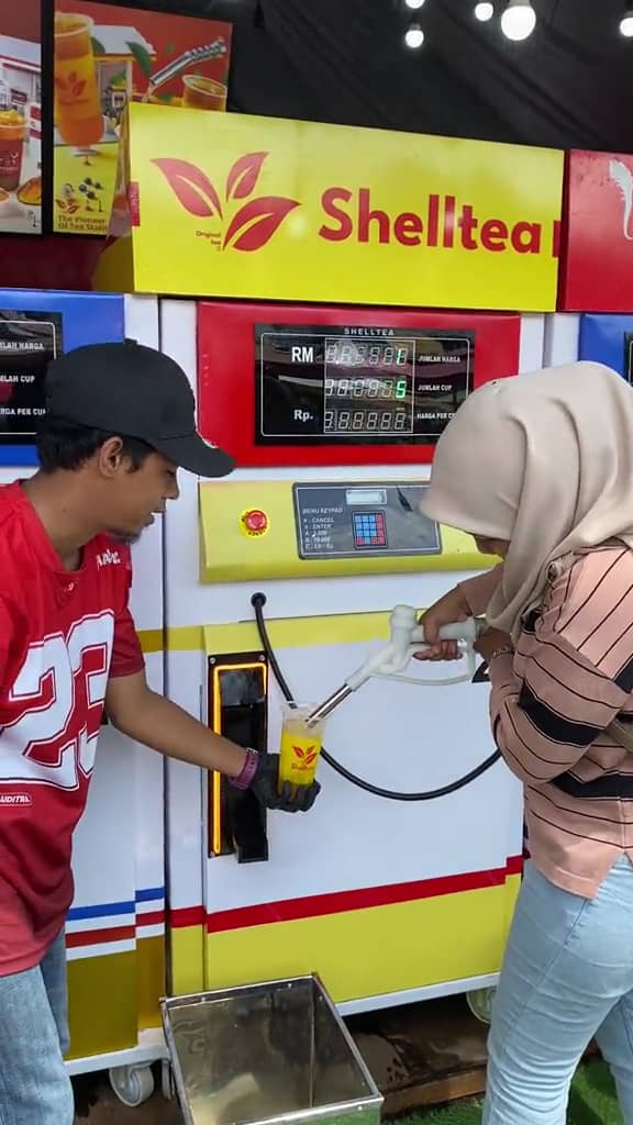 Msian woman filling up her drink in a cup using a petrol nozzle at melaka