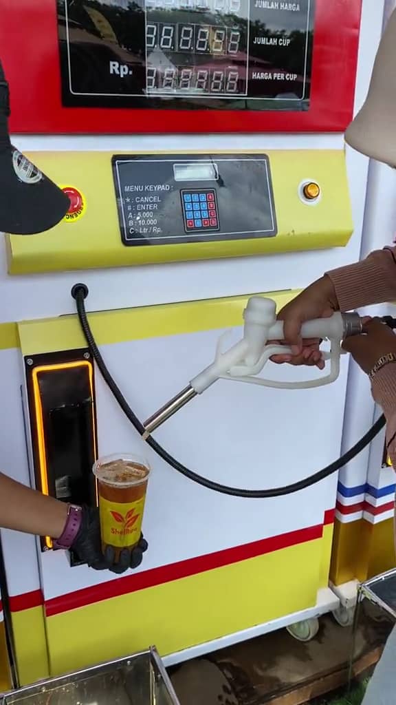 Msian woman pouring teh drink using the petrol nozzle into her cup