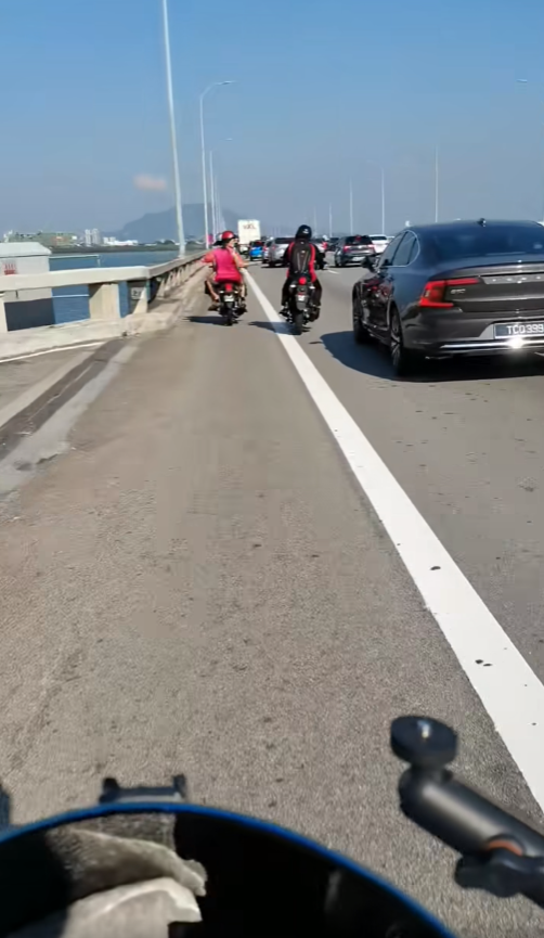 Msian woman throwing sand at other motor rider