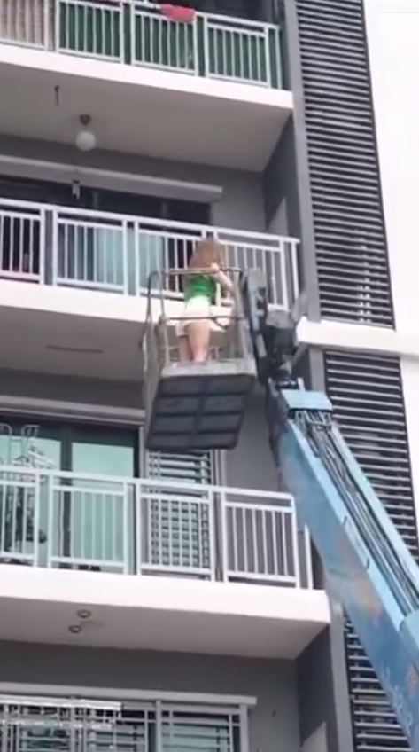 Msian woman using crane to enter her home through balcony