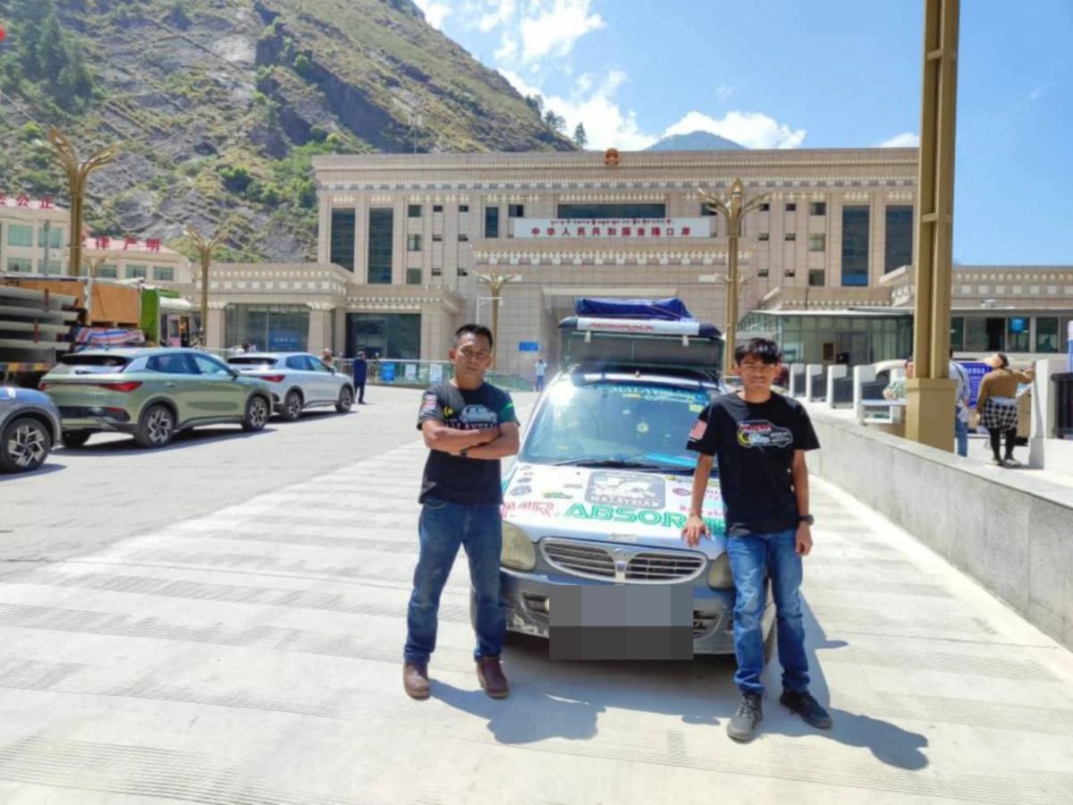 Nursulhi dan aidil posing near their car at a city