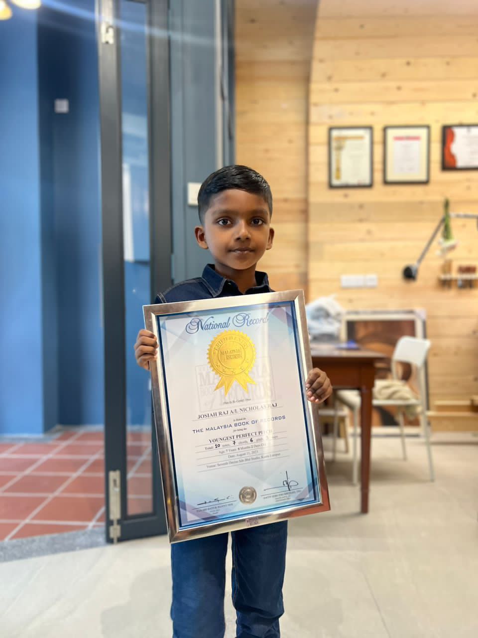 7yo josiah raj posing with his malaysian book of records award