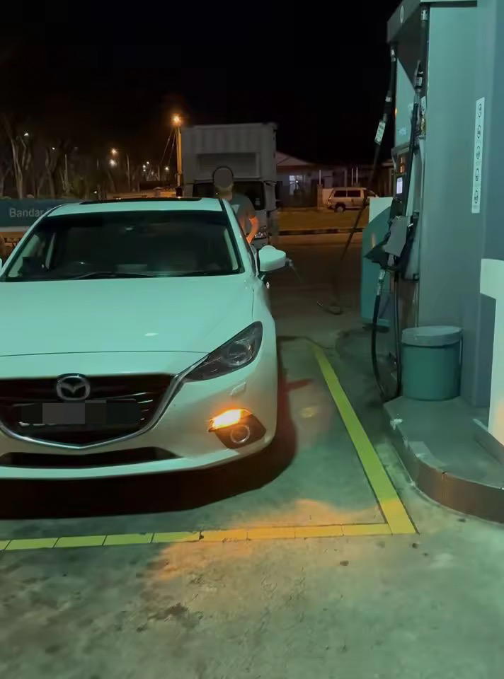 Photo of man caught pumping RON95 into SG-registered car