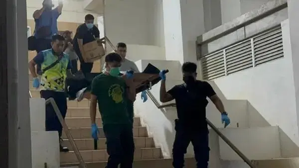 Police carrying dead body down the stairs at Penang flat