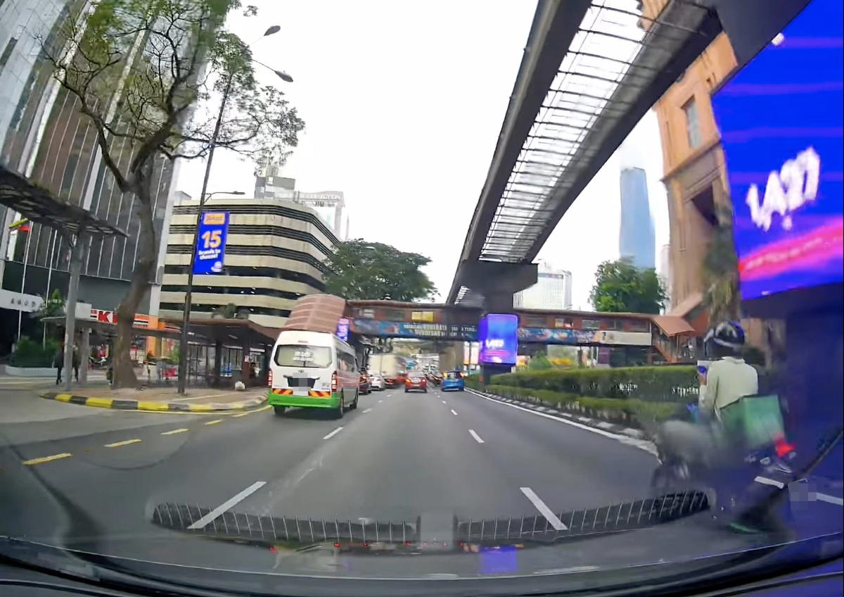 M'sian Delivery Rider Sitting Cross-Legged And Playing His Phone On His Motorcycle