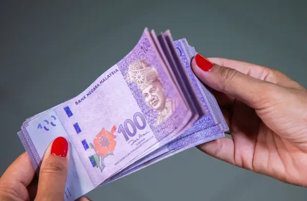 Woman holding a stack of malaysian ringgit