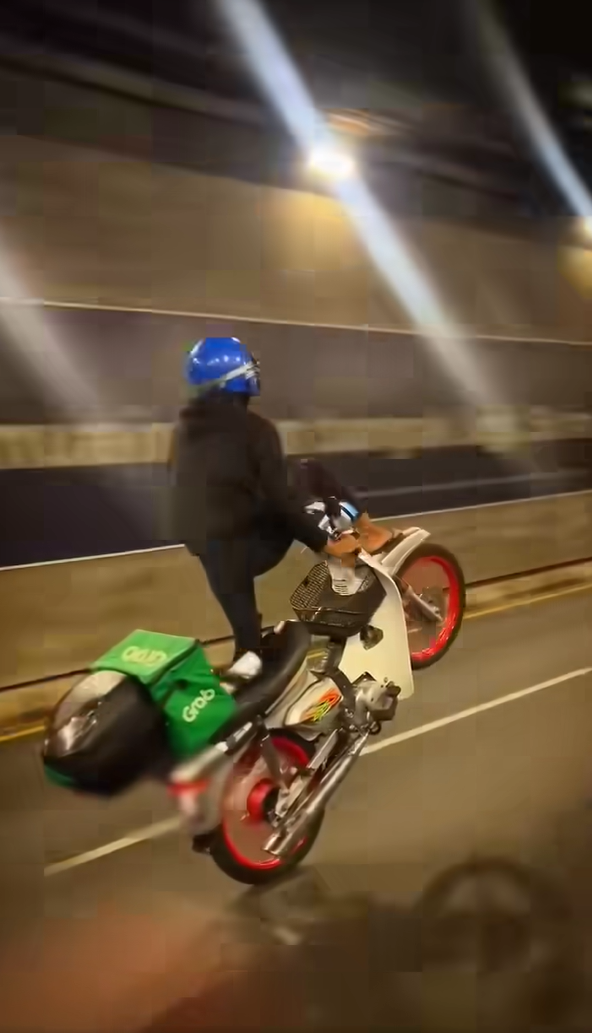 Delivery rider doing wheelie stunt with his motorbike