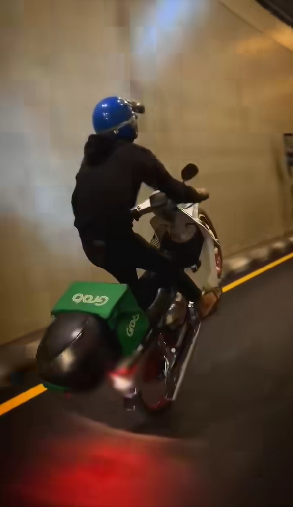 Delivery rider doing wheelie stunt with his motorbike