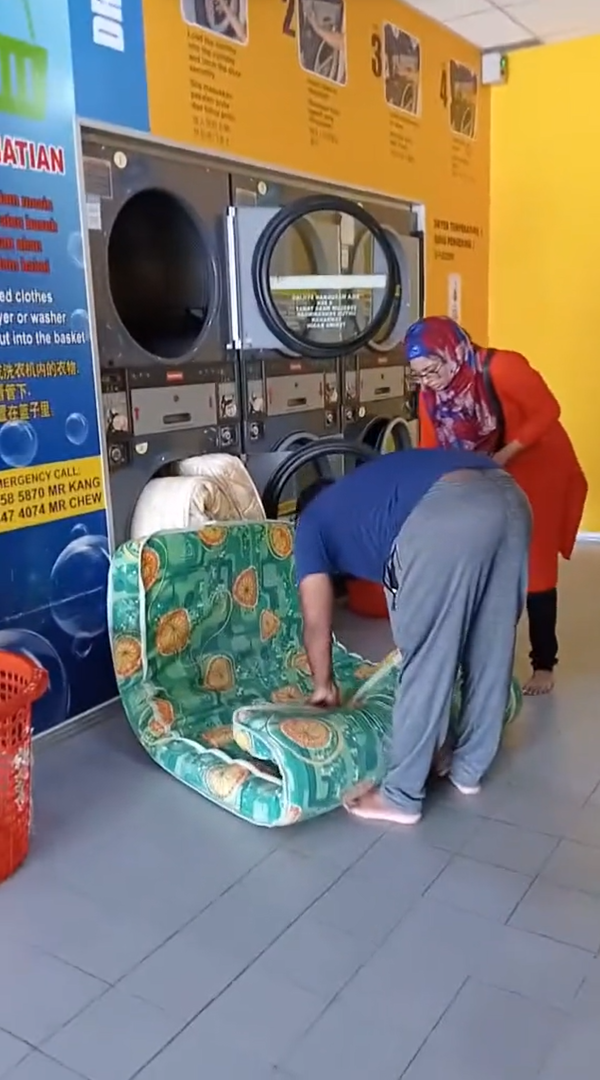 Man rolling up mattress at laundromat