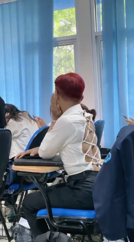 Male student sitting in a lecture class wearing revealing backless clothe.