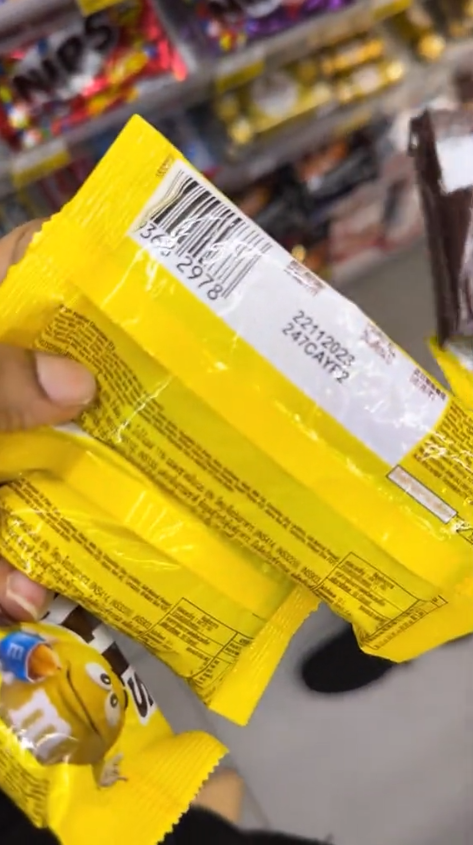 A m'sian woman is showing one of the expired chocolates that were displayed on the shelves at 7-eleven sentul.