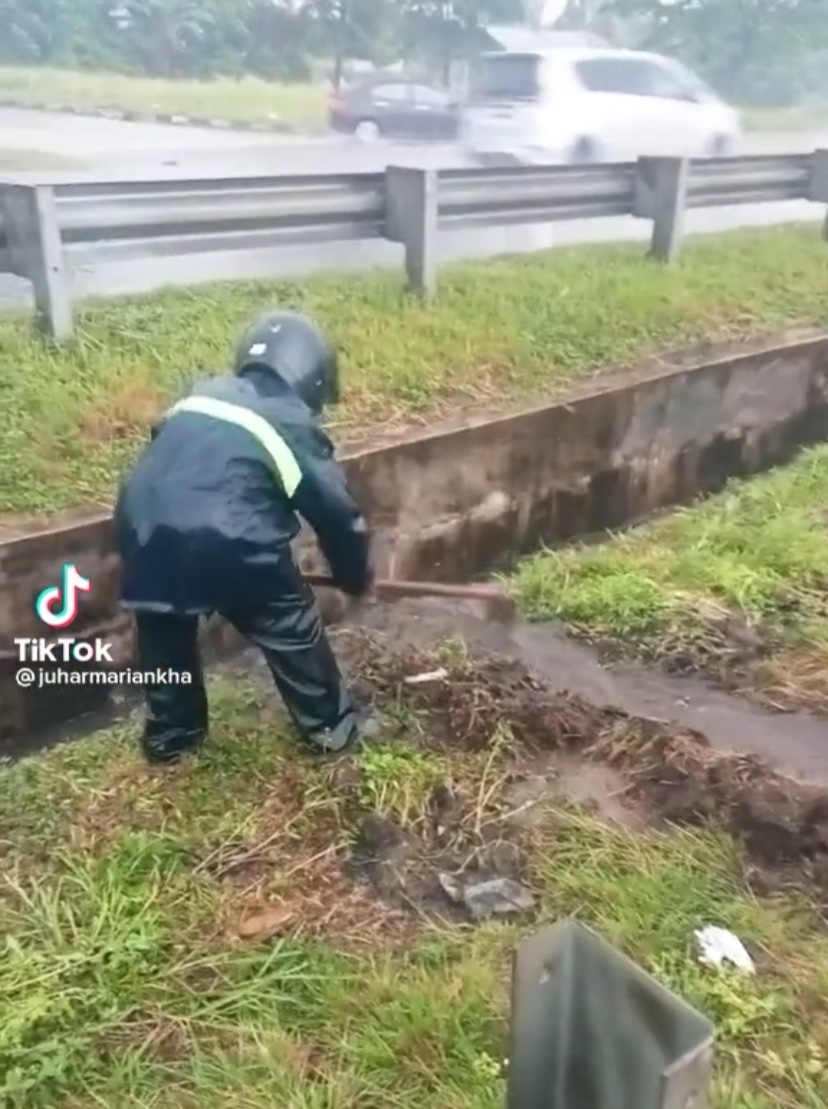 M'sian man drains flooded highway road by digging pathway under heavy rain