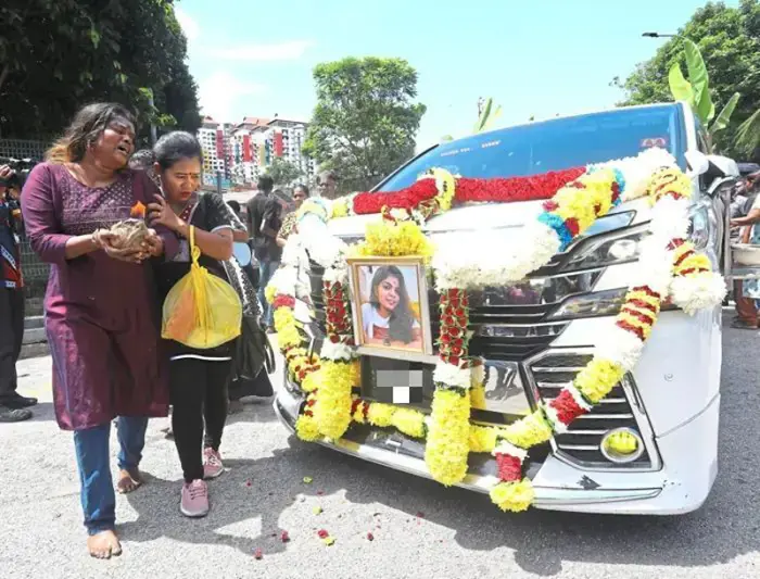 Susila (left) mourning her sister’s death during the funeral procession.