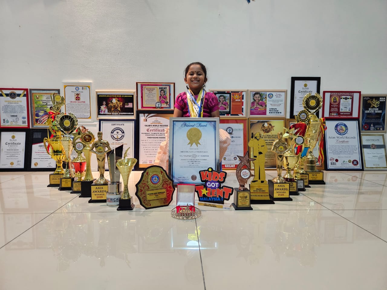 Thevissha sitting with all of her medals and record