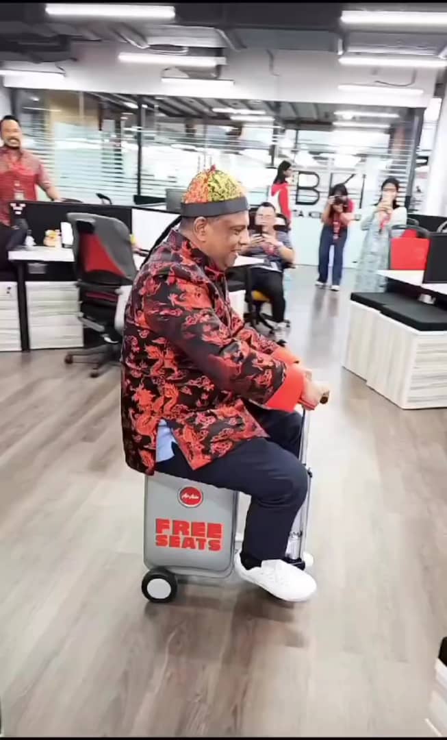 Tony fernandes riding a electric suitcase