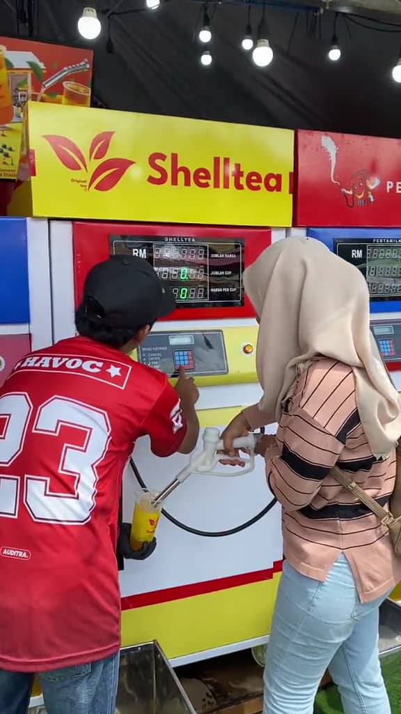 Vendor assisting his customer to access the drink at the petrol pump concept drink store.