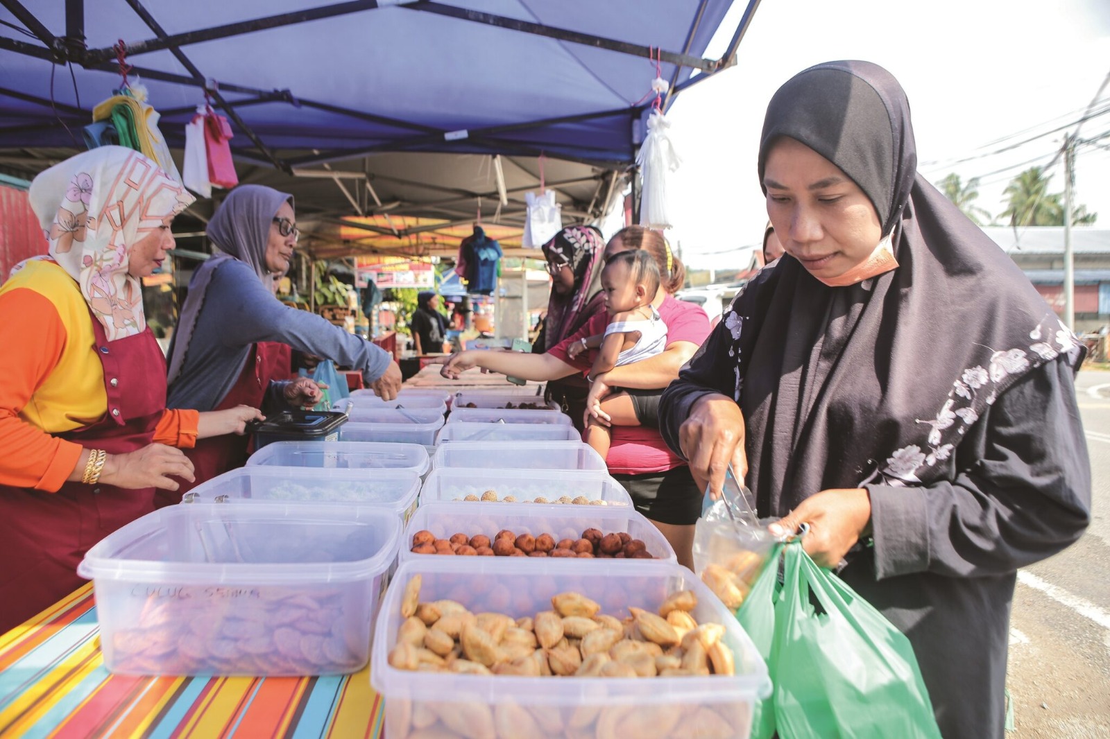 Customers buying from roslina saad's kuih stall in kedah