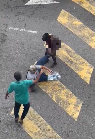 Naked foreigner pulling the legs of a man who had fallen on the road