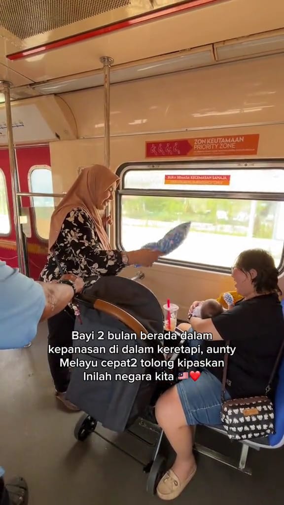 Msian woman fanning a mother and her baby in a bus while having a conversation with her