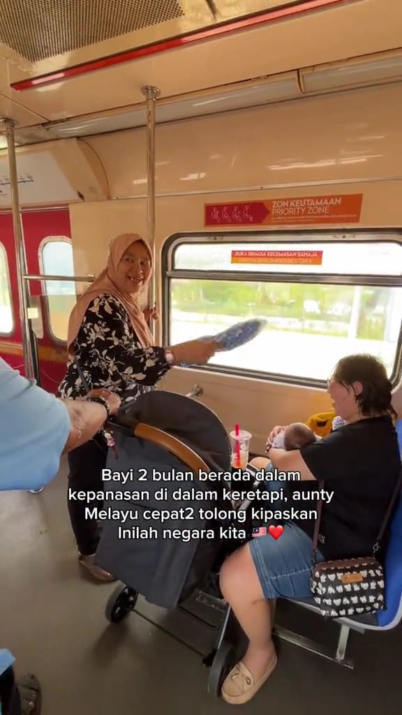 Msian woman fanning a mother and her baby in a bus