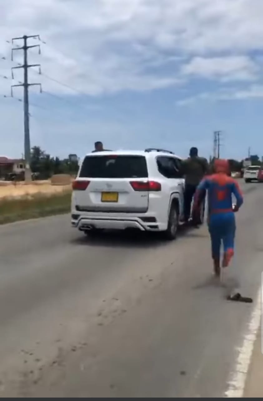 Msian dressed as spiderman running towards a car