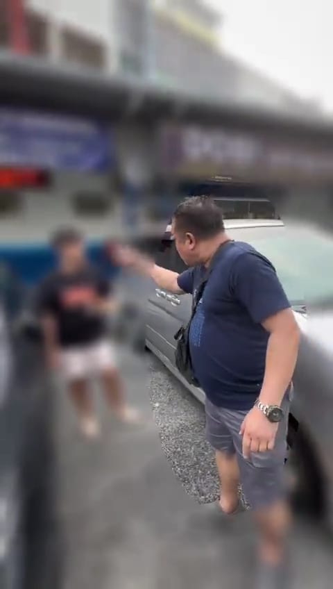 An angry msian man scolding a male student for turning on his headlights