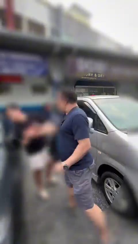A man slapping a student at a car parking spot