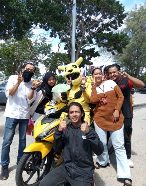 M'sian grab food rider in pikachu suit taking picture with people.