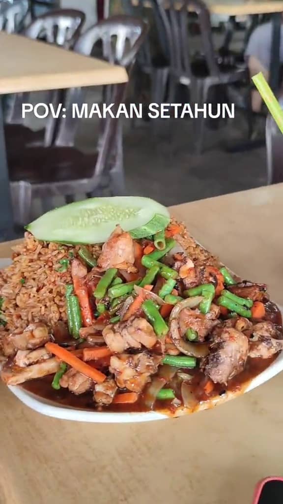 A m'sian shows the portion of fried rice that his friend received after ordering at a stall.  