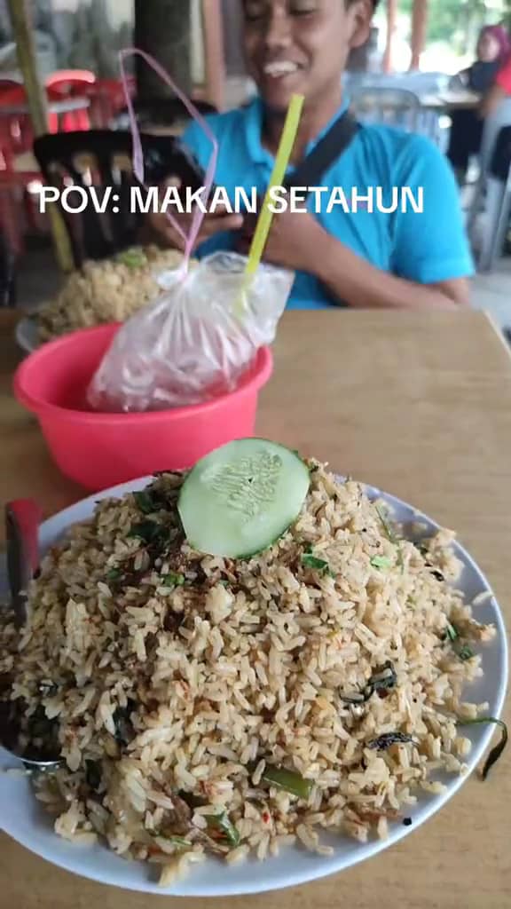 A m'sian shows the portion of fried rice that he received after ordering at a stall.  