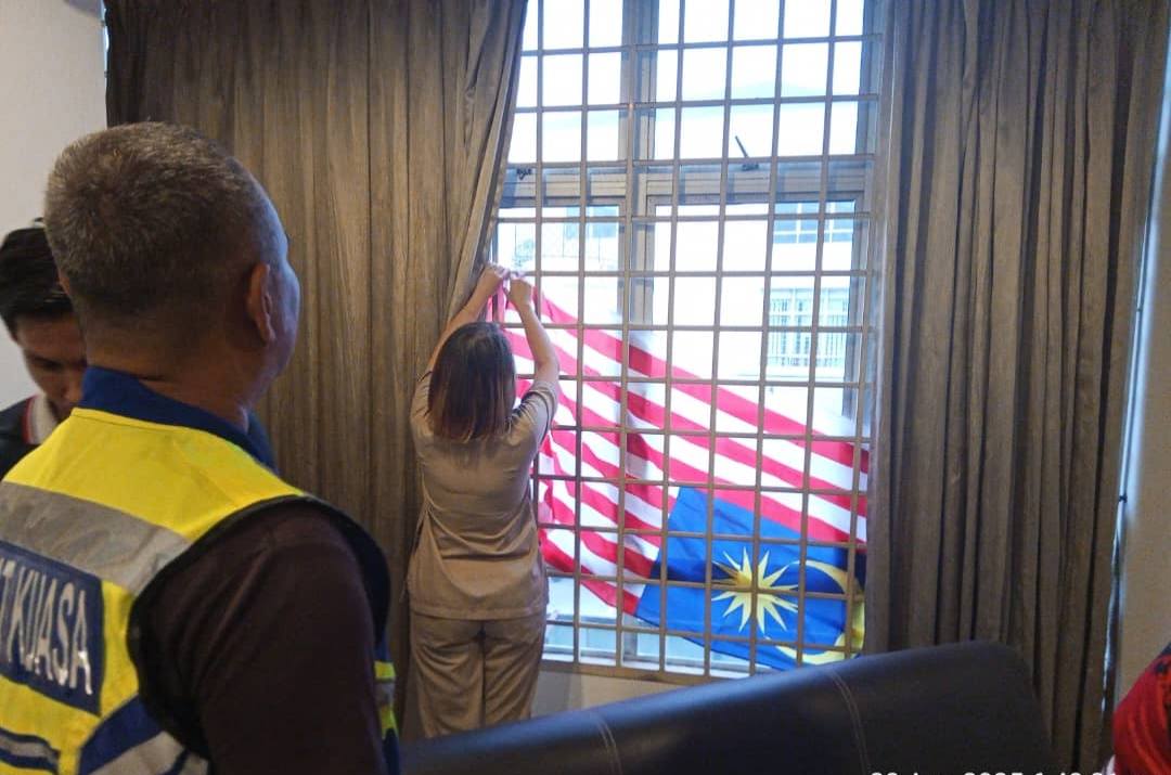 Woman correcting upside down Jalur Gemilang