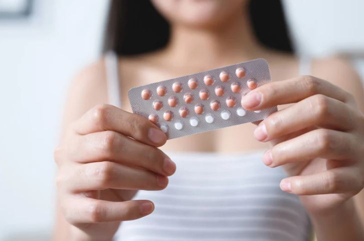 Woman holding birth control pills